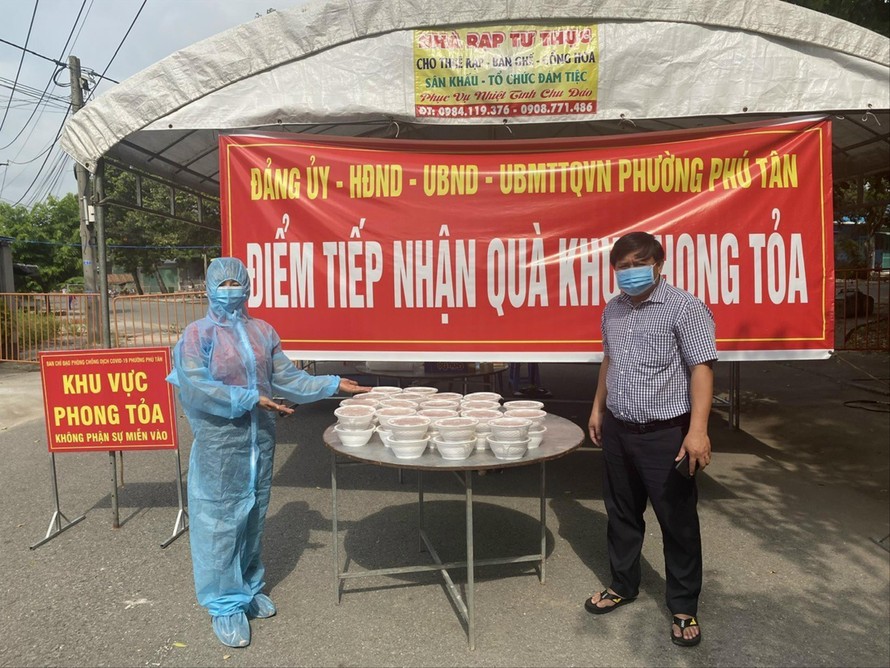Chị Lê Thị Minh (bìa trái) mang suất ăn đến khu vực phong tỏa Ảnh: H.C 