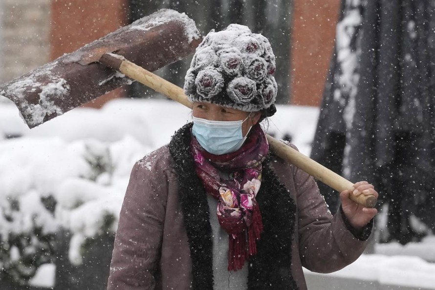 Mùa đông năm nay đến sớm ở nhiều tỉnh, thành phố Trung Quốc, khiến biến thể Delta dễ lây lan hơn. Trong ảnh, một phụ nữ vác xẻng đi giữa trời tuyết ở thủ đô Bắc Kinh ngày 7/11Ảnh: AP 