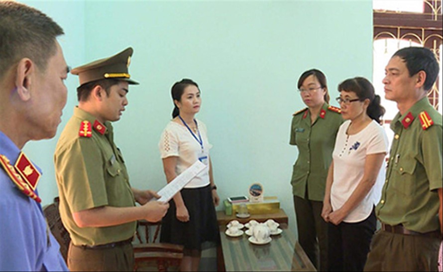 Bị can Nguyễn Thị Hồng Nga (áo trắng bên phải) nghe tống đạt quyết định khởi tố