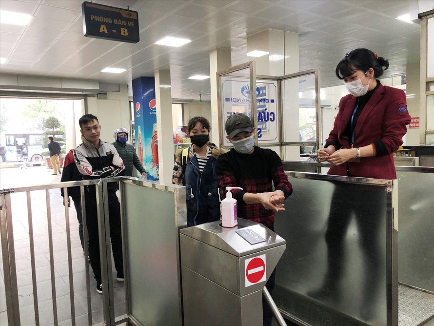 Hành khách được rửa tay sát khuẩn và phát khẩu trang miễn phí khi qua cửa soát vé tại bến Giáp Bát. Ảnh: T.Ðảng