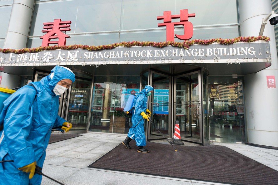 Nhân viên y tế phun thuốc diệt khuẩn bên ngoài trụ sở của sàn chứng khoán Thượng Hải .Ảnh: Getty Images 