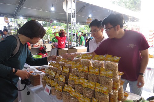 Chàng trai trẻ Tô Nhựt Điền (bên phải) giới thiệu bánh tráng kẹo cho khách hàng Ảnh: U.P 
