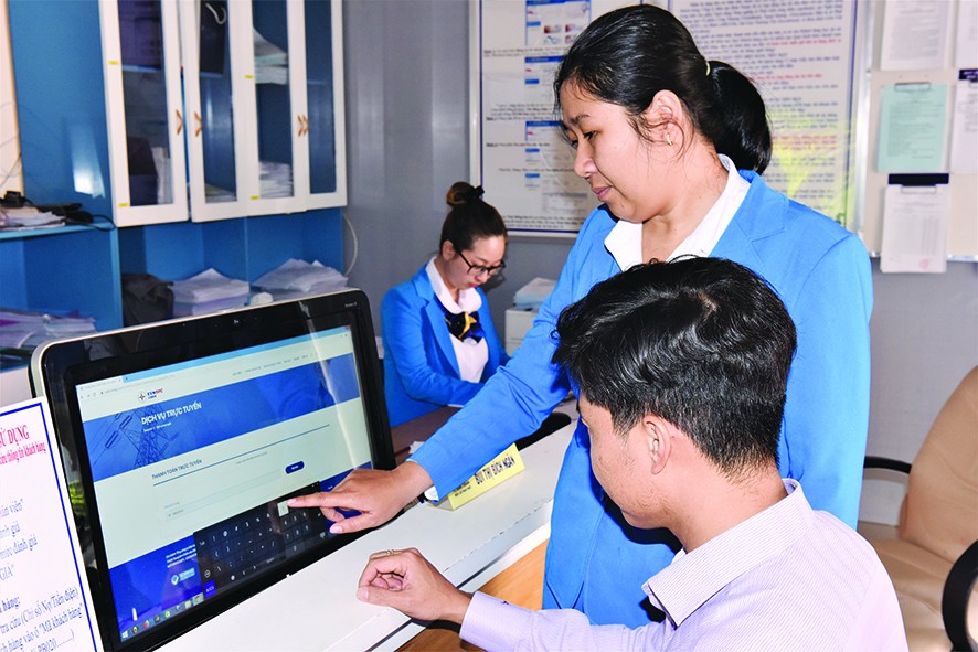 Nhân viên Công ty Điện lực Bình Thuận hướng dẫn khách hàng thao tác thanh toán tiền điện trực tuyến Ảnh: Văn Hơn 