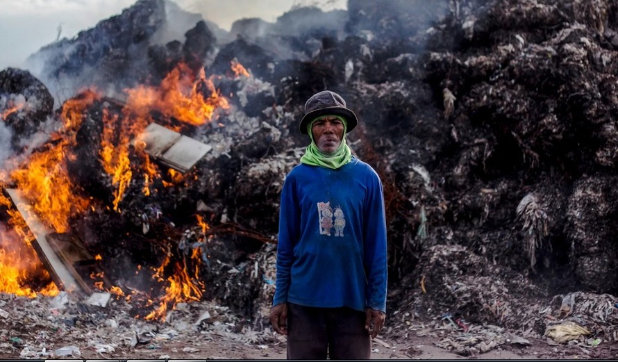 Một người làm nghề nhặt rác ở Indonesia đứng trước núi rác thải nhập khẩu đang bị đốt ảnh: EPA