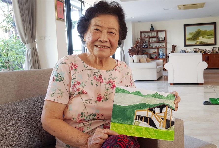 Bà Tú Anh với bức tranh vẽ ngôi nhà sàn, nơi đồng chí Hoàng Văn Thụ sinh ra và lớn lên Ảnh: kiến nghĩa