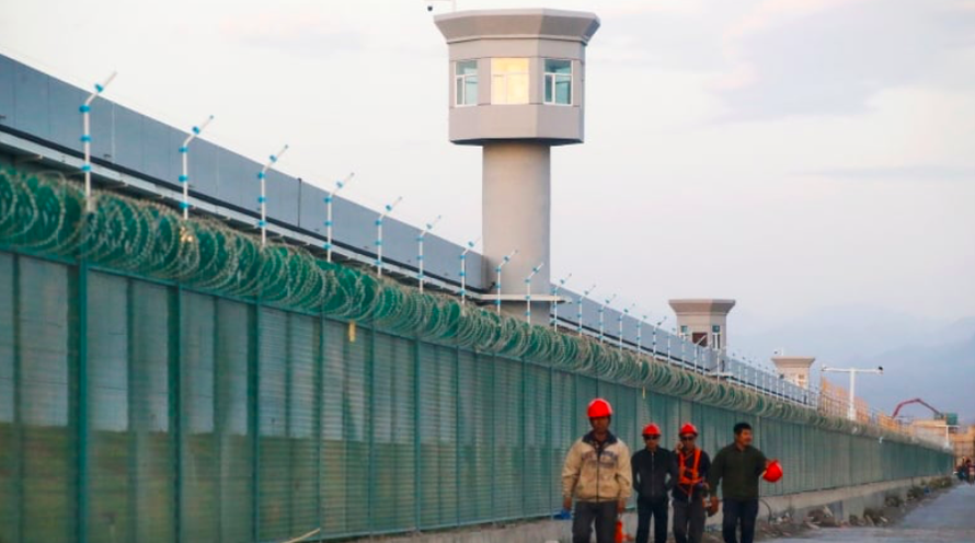 Một nhóm công nhân đi dọc hàng rào của trung tâm cải tạo ở Tân Cương Ảnh: Reuters