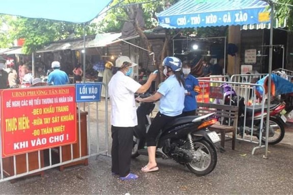 Đo nhiệt độ người dân trước khi họ vào chợ tại Hải DươngNguồn: QĐND
