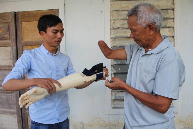 Ngô Văn Dết thử nghiệm “bàn tay robot”với ông Lê Quang Trọng. Ảnh: N.N 