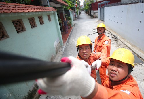 Công nhân điện lực Hà Nội sửa chữa đường dây điện sinh hoạt tại quận Long Biên. Ảnh: VnEpress