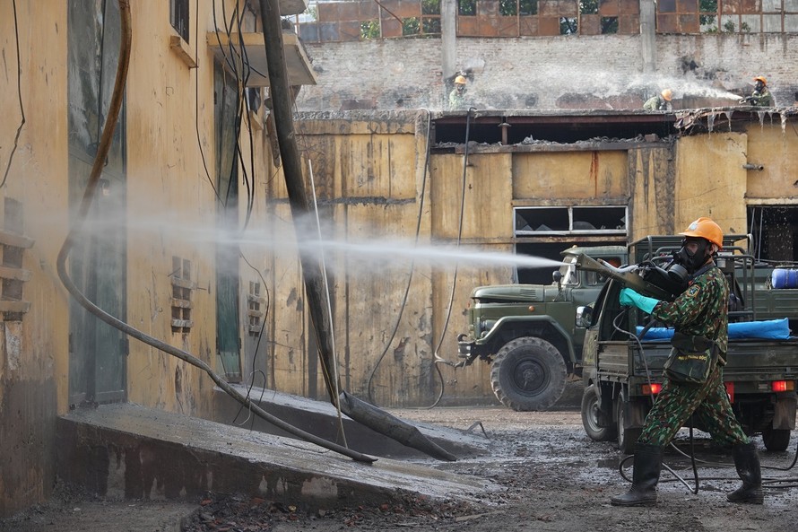 Chiến sĩ phòng hóa dùng súng phun hóa chất tẩy độc các bức tường 