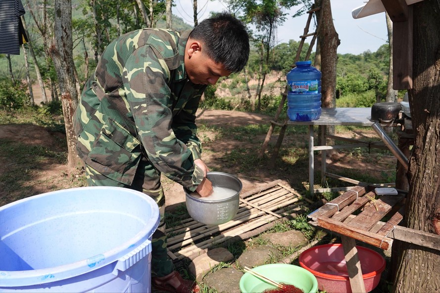 Trung úy Nguyễn Giai Hưng vo gạo nấu cơm trưa tại chốt chống dịch trên bến Cổ Thành ẢNH: NGUYỄN MINH 