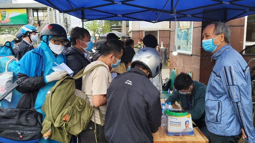 Người dân đến thăm khám, đưa đồ tiếp tế cho người nhà phải xếp hàng dài đo thân nhiệt trước khi vào bệnh viện Bạch Mai (Hà Nội)