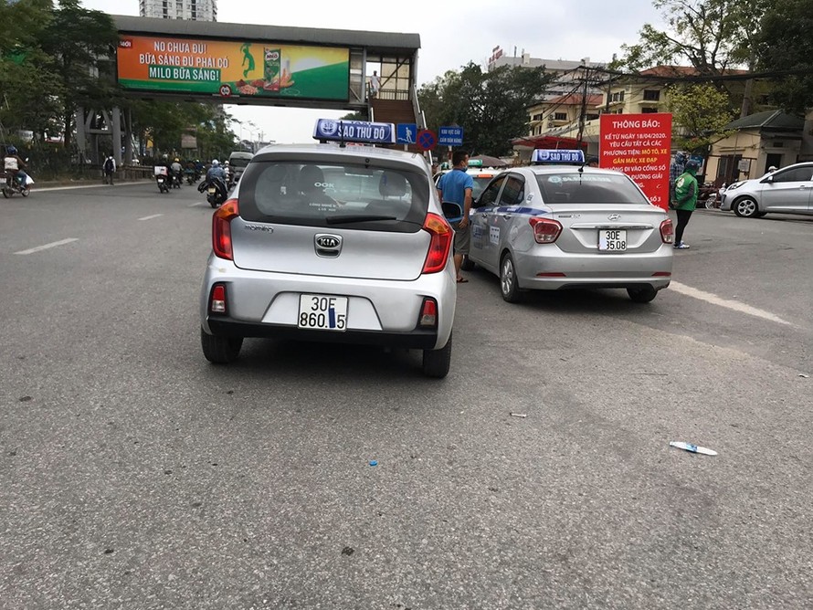 Taxi che biển số, đỗ tràn dưới lòng đường, trước cổng Bệnh viện Bạch Mai chèo kéo khách.