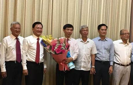 Phó Chủ tịch UBND TPHCM Võ Văn Hoan (thứ ba từ phải qua) trao quyết định và tặng hoa chúc mừng ông Nguyễn Văn Tám