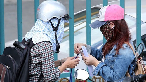Sinh viên H.N (phải) gửi thẻ sinh viên nhờ phóng viên thi hộ ngay trước cổng trường - Ảnh: Đào Ngọc Thạch