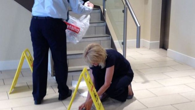 Nhân viên ngân hàng đang dọn dẹp đống phân trên sàn. Ảnh: Metro 