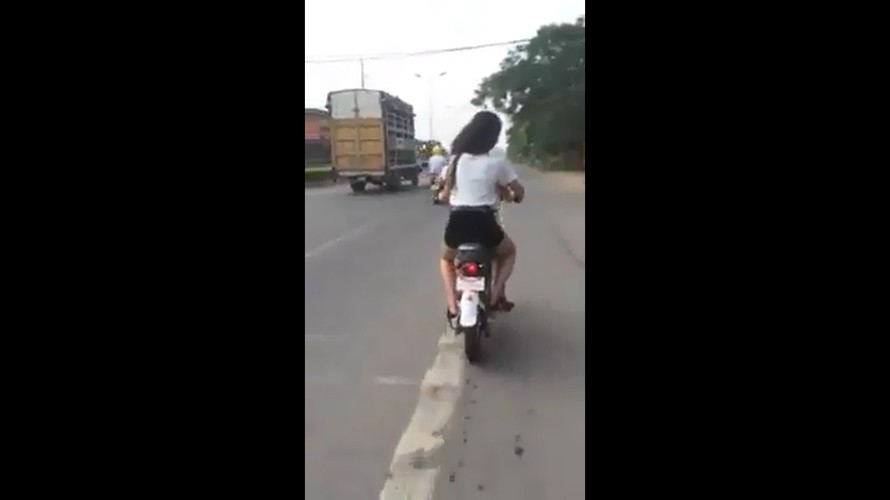 Hai cô gái đi xe đạp điện đánh võng trên đường