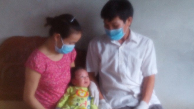 Mỗi lần bế con, vợ chồng chị Ngà, anh Tuấn phải đeo găng tay, khẩu trang để tránh nguy cơ lây nhiễm bệnh cho bé. Ảnh: Lê Mai.