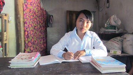 Em Nguyễn Thị Phượng bên góc học tập đơn sơ, ba chị em dùng chung một đèn học, một chiếc bàn.