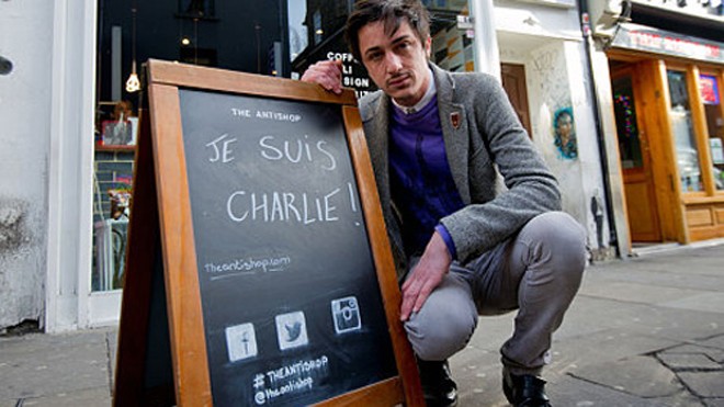 Ông chủ Adel Defilaux bên tấm biển ghi "Je Suis Charlie" đặt trước cửa quán cà phê của mình. Ảnh: Telegrpah.