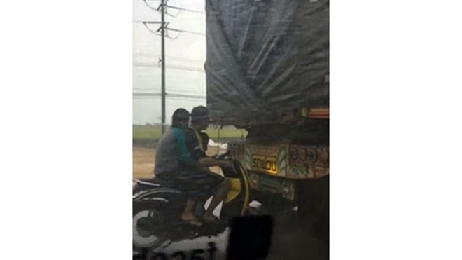 Chạy xe máy dí sát đuôi xe tải để... tránh mưa