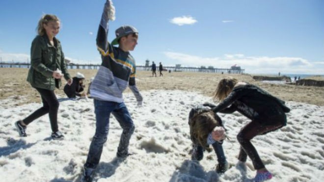Trẻ em chơi đùa trên bãi biển Huntington trắng xóa sau trận mưa đá. 