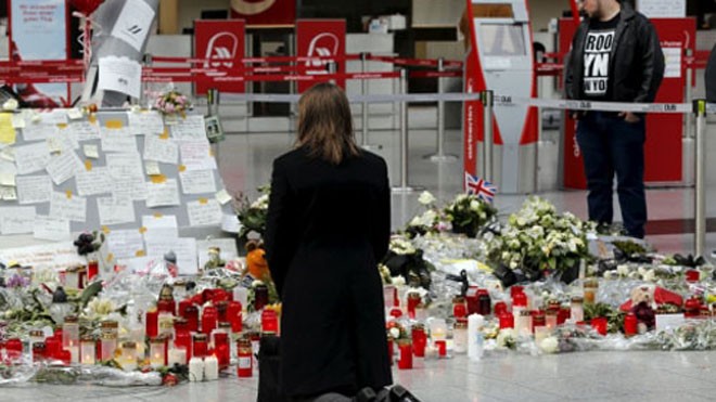 Một phụ nữ quỳ gối trước hoa và nến cầu nguyện cho các nạn nhân trên chuyến bay xấu số 9525 tại sân bay Dusseldorf, Đức. Ảnh minh họa: Reuters.