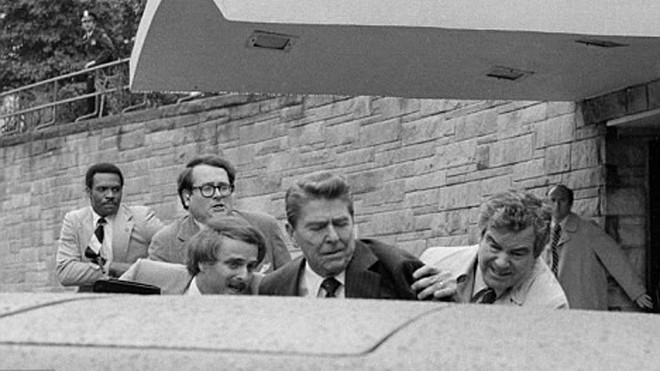 Nhân viên an ninh vội vã đưa Tổng thống Reagan (giữa) vào xe limousine sau khi ông bị bắn vào ngực. Ảnh: AP