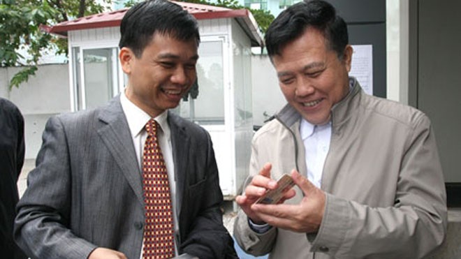 Ông Nguyễn Văn Quyền (phải) chúc mừng anh Cường, người đầu tiên nhận GPLX qua khai báo điện tử.