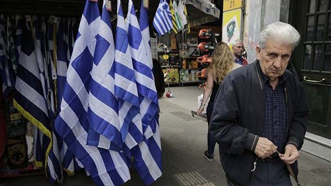 Người đàn ông đi qua một ki ốt bán cờ tại Athens. Ảnh: MB