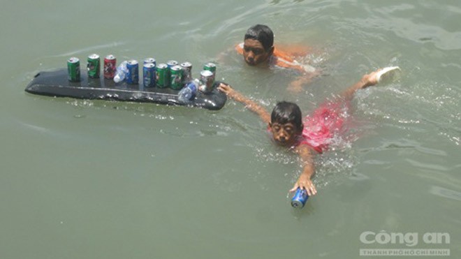 "Người nhái" nhí lượm lon bia, chai nhựa để bán ve chai - Ảnh: Phan Sơn