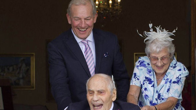 Cụ ông George cười mãn nguyện khi được vợ mới cưới đẩy đi bằng chiếc xe lăn