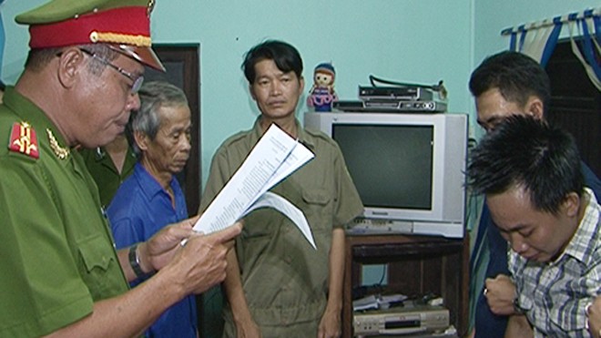 Trần Xuân Vinh (bìa phải) bị Công an Thừa Thiên – Huế đọc lệnh khởi tố tại nhà. Ảnh: T.Bình