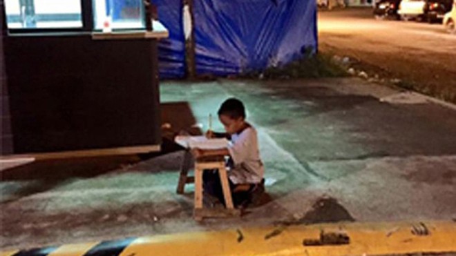 Daniel say sưa làm bài tập bằng ánh đèn đường hắt lên vỉa hè thủ đô Manilla, Philippines, hình ảnh đã gây xúc động mạnh cho cộng đồng mạng quốc gia Đông Nam Á và thế giới (Ảnh: Torrefranca)