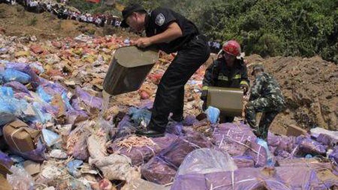 Các sĩ quan rưới xăng đốt số thịt buôn lậu tịch thu được ở Vân Nam, Trung Quốc hôm 8-7-2015 - Ảnh: Reuters/China Daily