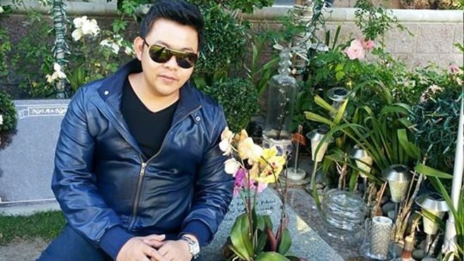 Ảnh Quang Lê ngồi trên mộ bị chỉ trích. Ảnh: Facebook NV