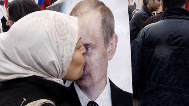 Một phụ nữ Syria hôn ảnh chân dung của Tổng thống Putin trong cuộc tuần hành ủng hộ chính phủ ở thủ đô Damascus. Ảnh: AP