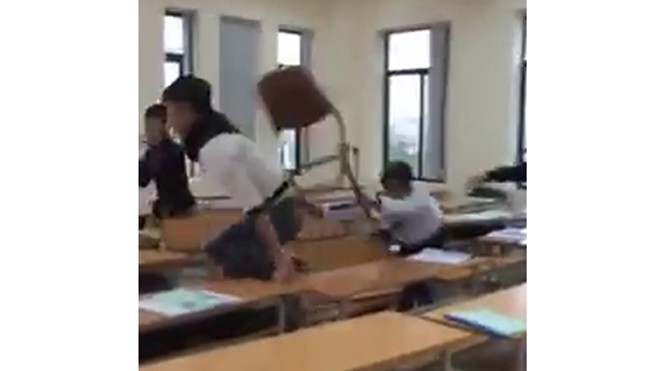 Nhóm sinh viên cao đẳng du lịch vác vả ghế đánh nhau trong phòng học. Ảnh cắt từ clip.
