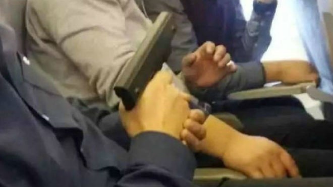 Bức ảnh người đàn ông cầm súng chĩa vào hành khách trên một máy bay ở sân bay quốc tế Bắc Kinh đăng trên mạng. (Ảnh: Sina)
