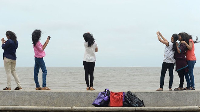 Khách du lịch chụp ảnh selfie trên bãi biển ở thành phố Mumbai. (Ảnh: AFP)