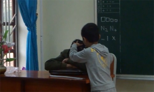 Hình ảnh thầy Tưởng gục trên bàn cho học sinh nhổ tóc. Ảnh: Cắt từ clip.