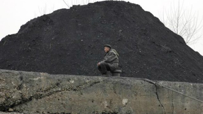 Một người đàn ông Triều Tiên ngồi bên một đống than ở thị trấn Sinuiju, Triều Tiên. Ảnh: Reuters