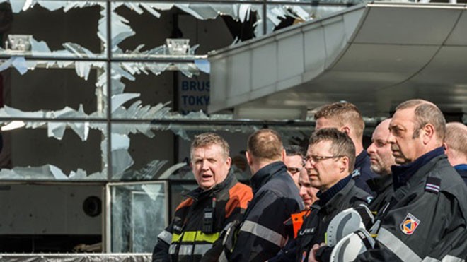 Các nhân viên phản ứng nhanh và lính cứu hỏa đứng bên ngoài sân bay Zaventem với những khung cửa sổ bị vỡ vụn bởi sức ép từ vụ nổ hôm 22/3. Ảnh: AP