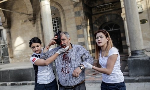 Nhân viên cứu hộ giúp một người đàn ông bị thương sau khi nhà thờ ở thị trấn Kilis bị trúng rocket ngày 24/4. Ảnh: AFP.