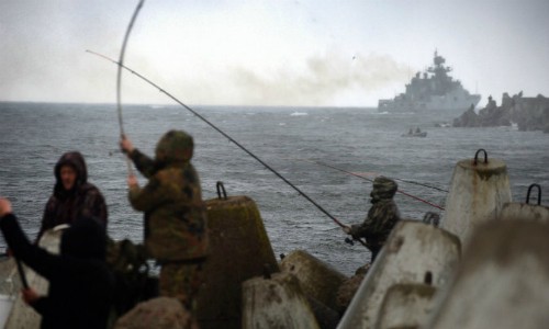 Ngư dân ở Kaliningrad câu cá khi một tàu chiến trong hạm đội biển Baltic của Nga rời cảng. Ảnh: NYTimes