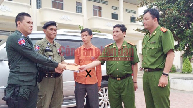 Đối tượng truy nã Chan Leang Hay mặc áo màu cam đứng giữa ảnh được Công an Việt Nam trao trả cho Cảnh sát Campuchia.