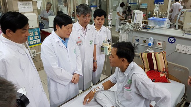 Thứ trưởng Bộ Y tế Nguyễn Viết Tiến (đứng thứ 2 từ trái sang) hỏi thăm bệnh nhân Quang vừa từ bệnh viện Đa khoa Hòa Bình chuyển về Bạch Mai (Hà Nội) - Ảnh: Hồng Hải
