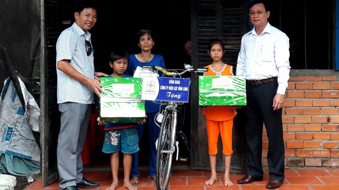 Đại diện báo Tiền Phong và Công ty Điện lực tỉnh Vĩnh Long trao quà cho em Lý Lam Chiều và em trai Lý Gia Trường.