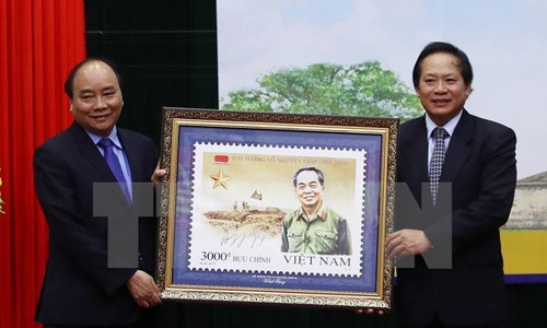 Bộ trưởng Bộ Thông tin và Truyền thông Trương Minh Tuấn thực hiện nghi thức trao tặng bộ tem cho Thủ tướng Nguyễn Xuân Phúc. (Ảnh: Thống Nhất/TTXVN)