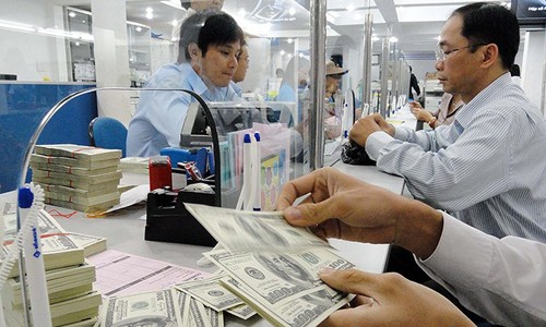 Đồng đôla Mỹ tăng tác động cả tích cực lẫn tiêu cực đối với DN Việt. Trong ảnh: Một khách hàng đang giao dịch ngoại tệ. Ảnh: TL